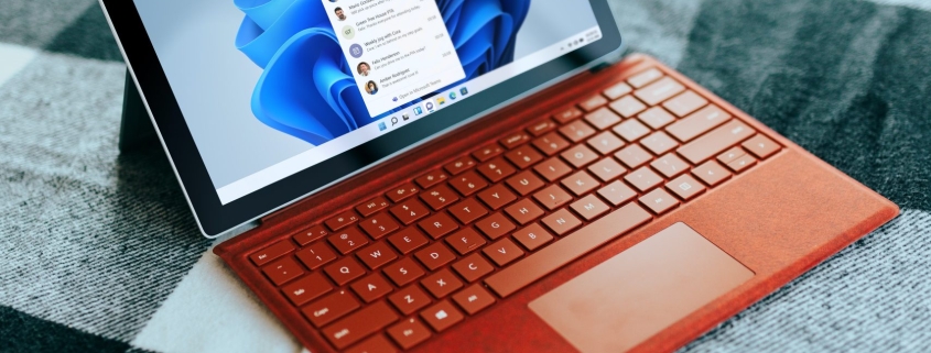 Red Surface laptop on a checkered bed by a window